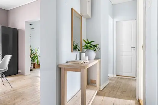 Bright hallway interior featuring minimalist decor, a mirror, and lush plants for a serene ambiance.